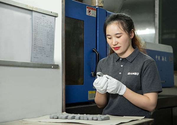 a female worker is checking plastic parts besides an injection machine